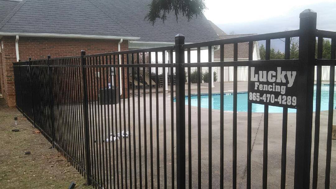 Black aluminum pool fence with a Lucky Fencing sign