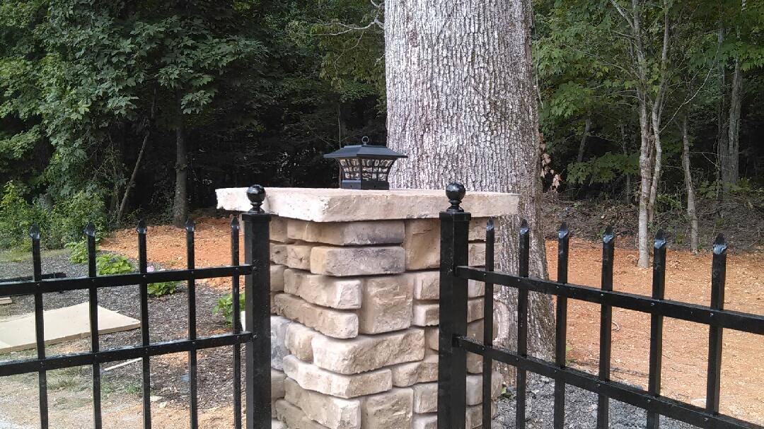 Black aluminum fence set between stone columns