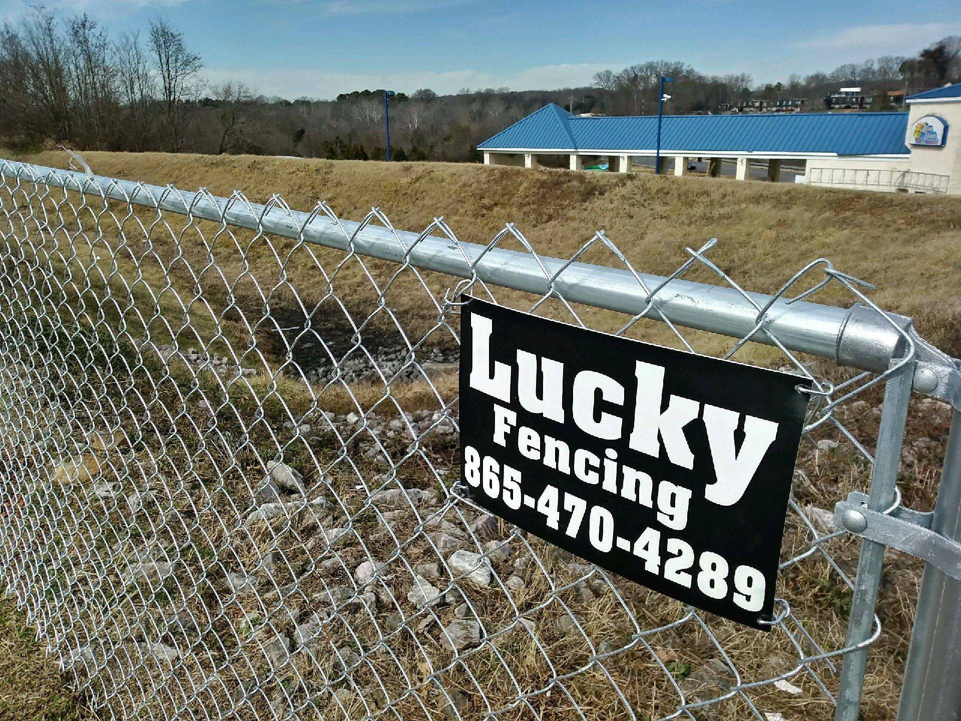 Chain link fence with a Lucky Fencing sign and phone number
