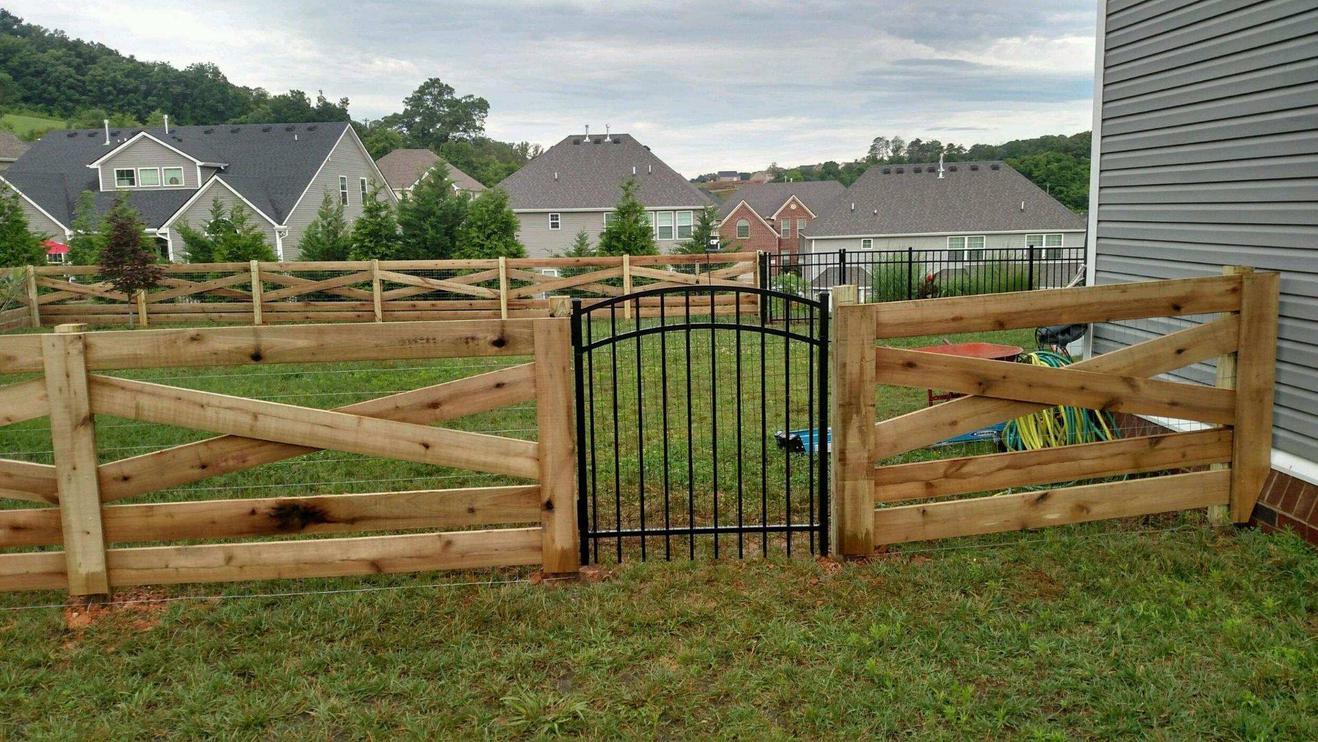 Crossbuck wood rail fence with a black arched walk gate