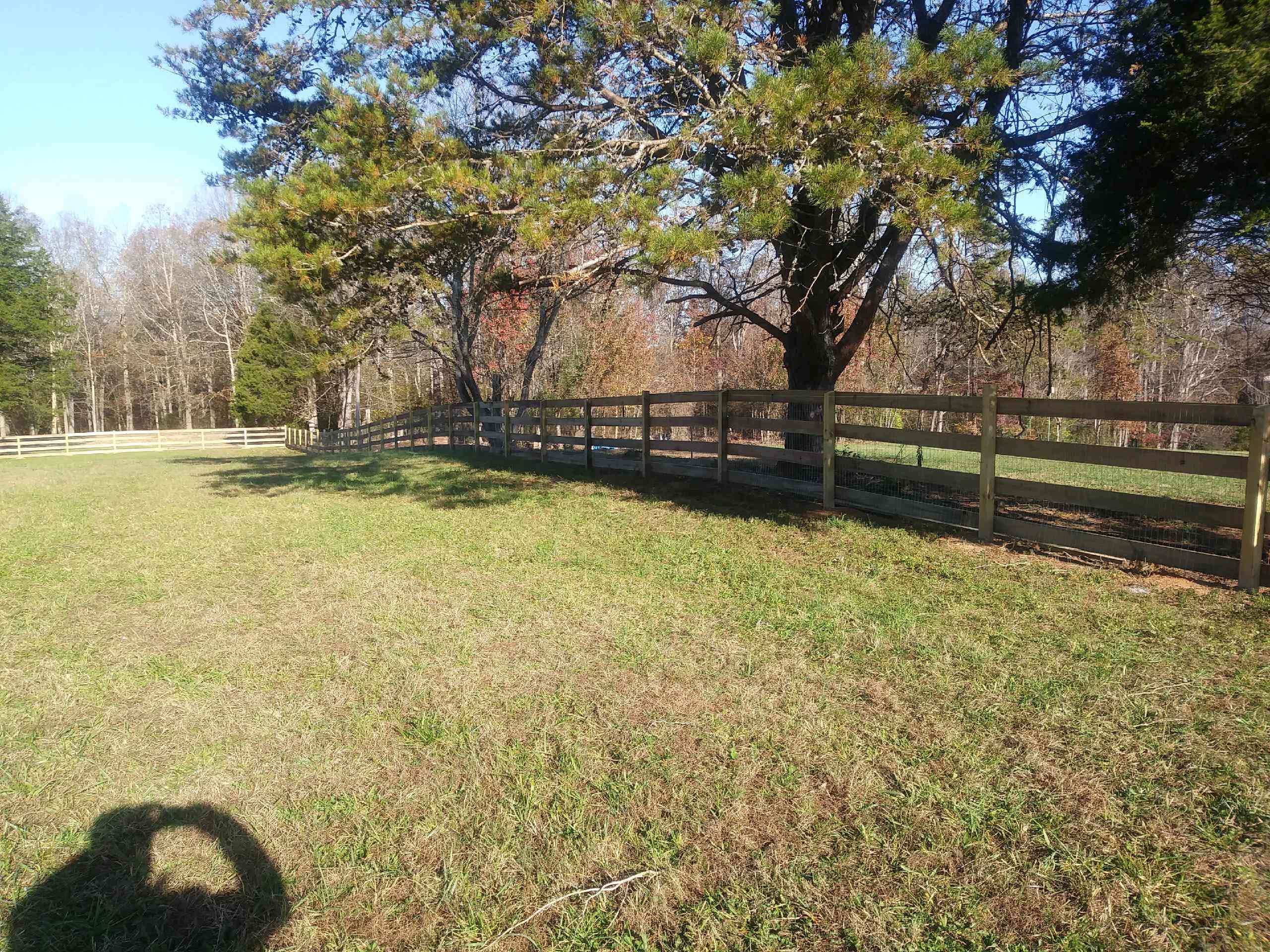 Dark four-board wood fence along an open field