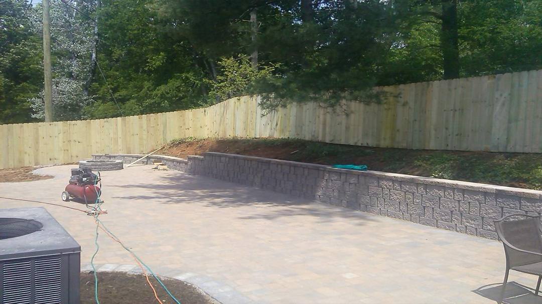 Wood privacy fence around a stone patio and retaining wall