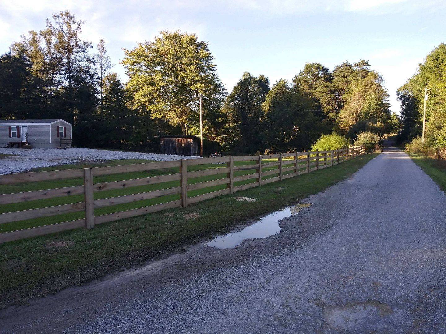 Four-board wood fence along a gravel drive