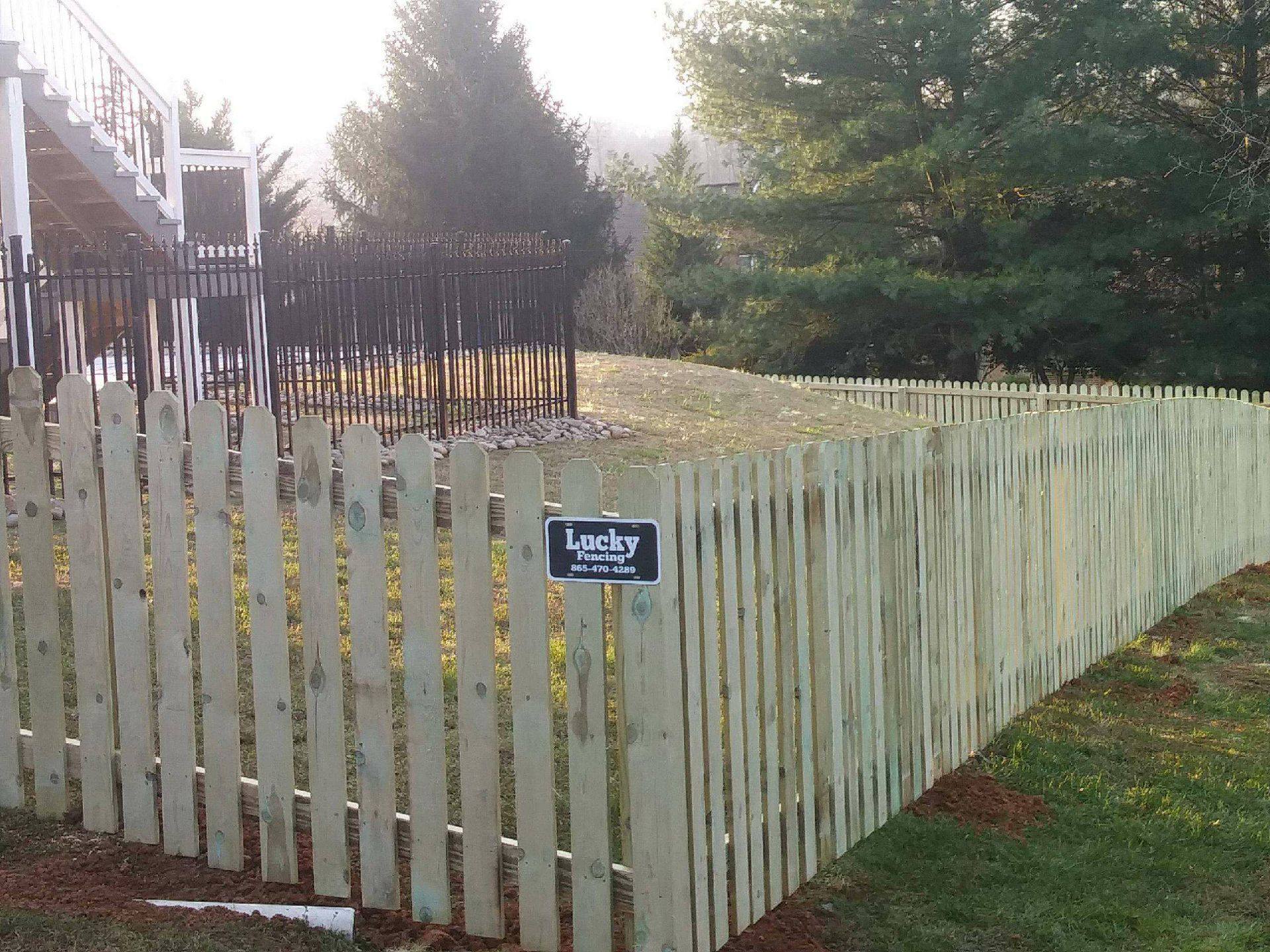 Spaced wood picket fence with a Lucky Fencing sign