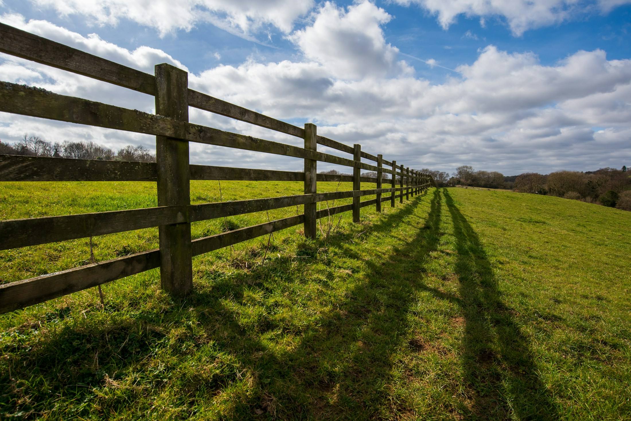 Long wooden rail fence across a green field