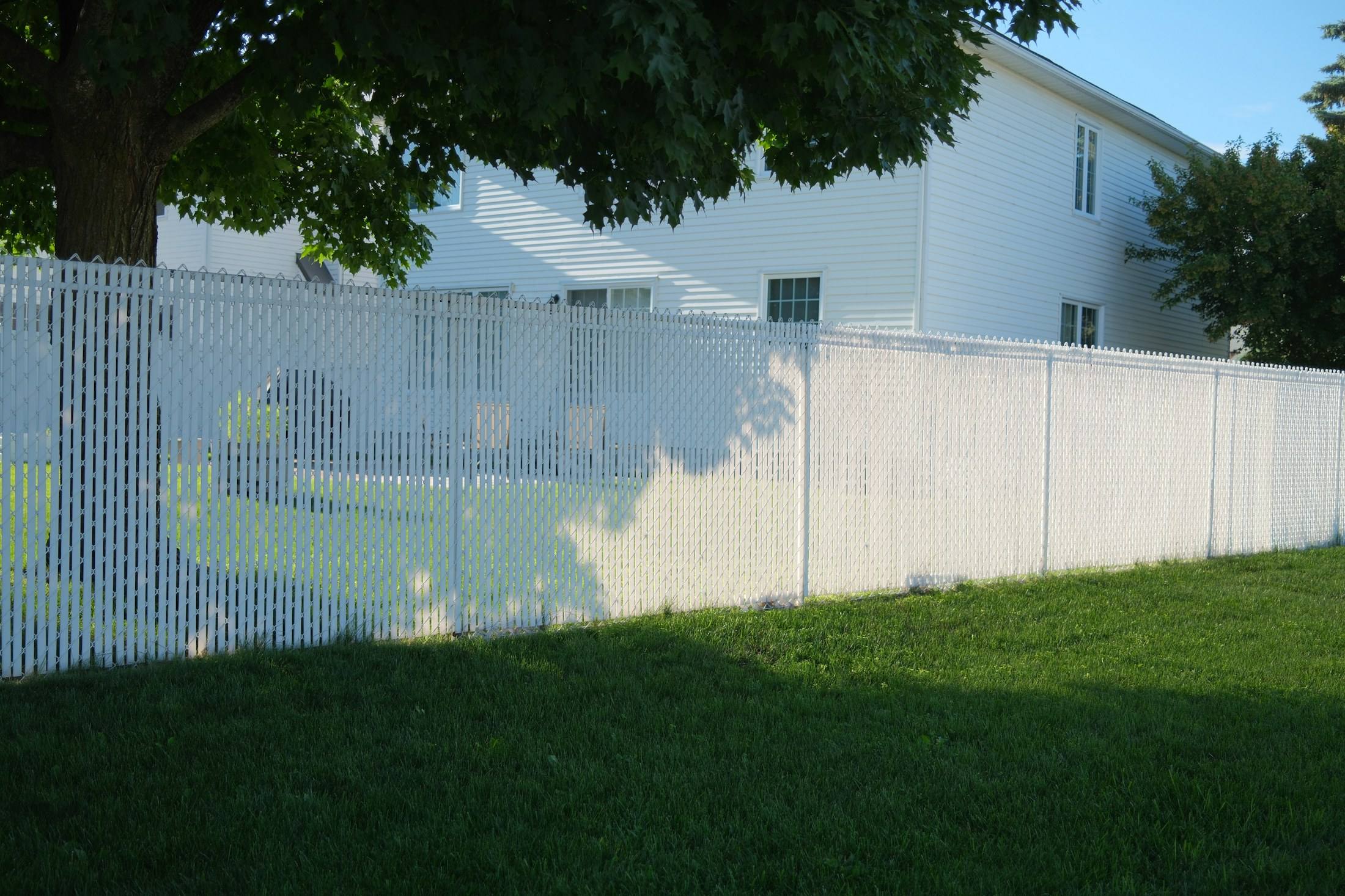 White privacy fence along a lawn beside a house